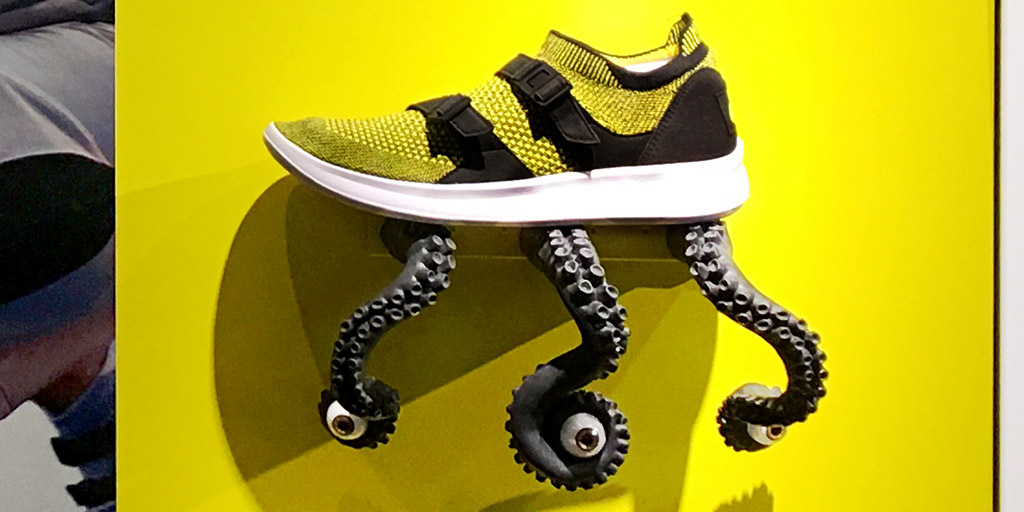 Image of a shoe resting on three tentacles with eyeballs mounted on the wall