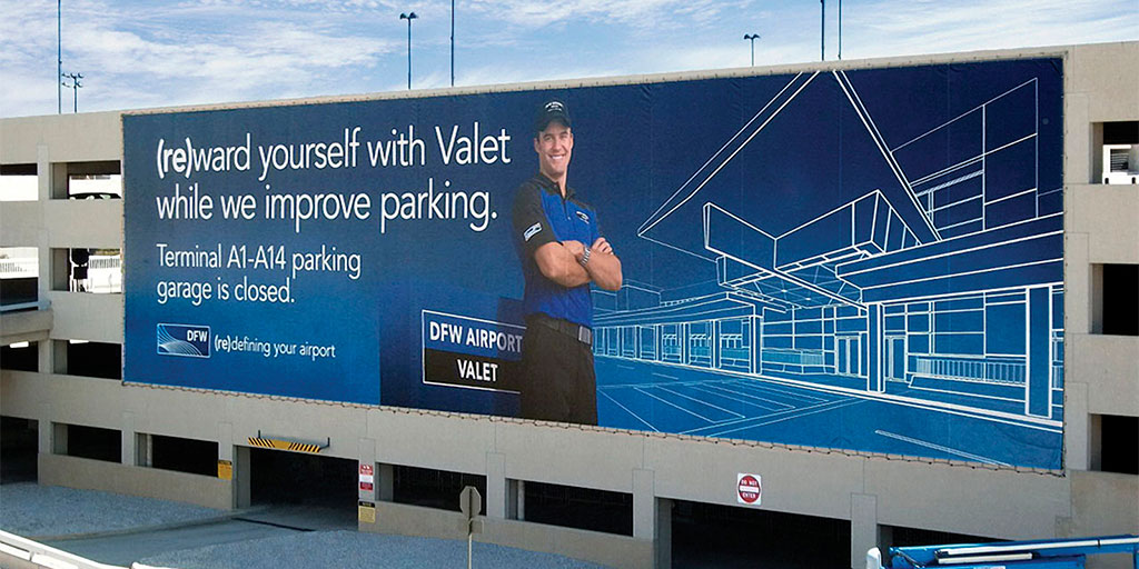 Image of the exterior of a parking garage with a billboard spanning across the side