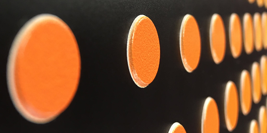 Image of black background with orange dots raised from the surface