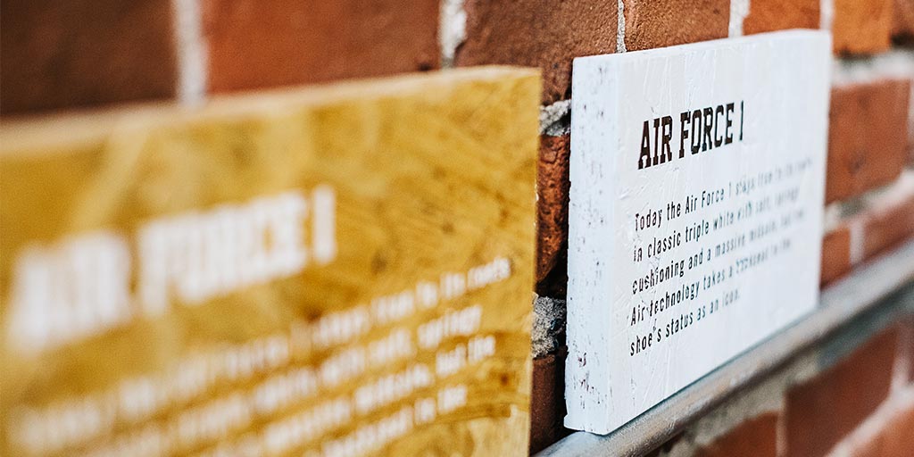 Image of two signs printed on chipboard, one white and one natural wood