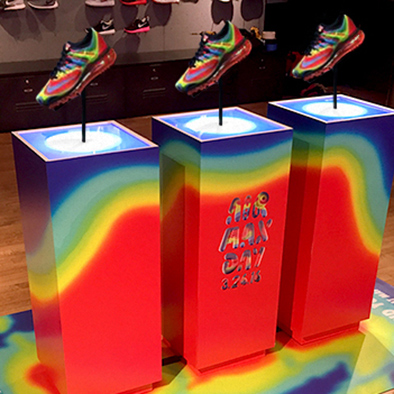 Image of pedestals with rainbow colors printed on them, displaying shoes with matching color pattern