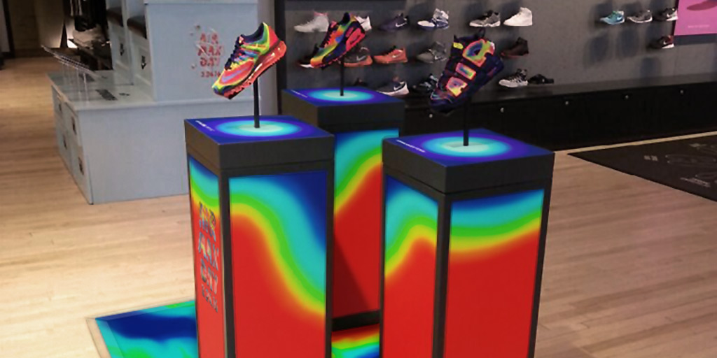 Image of three matching pedestals with rainbow gradients printed on sides and top, matching the shoes displayed on them